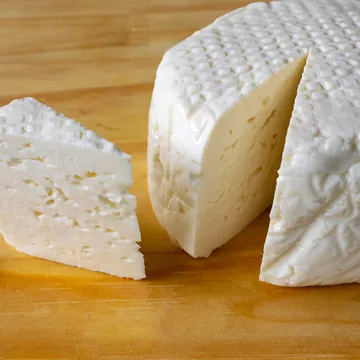 Queijo Minas Frescal redondo com uma fatia cortada